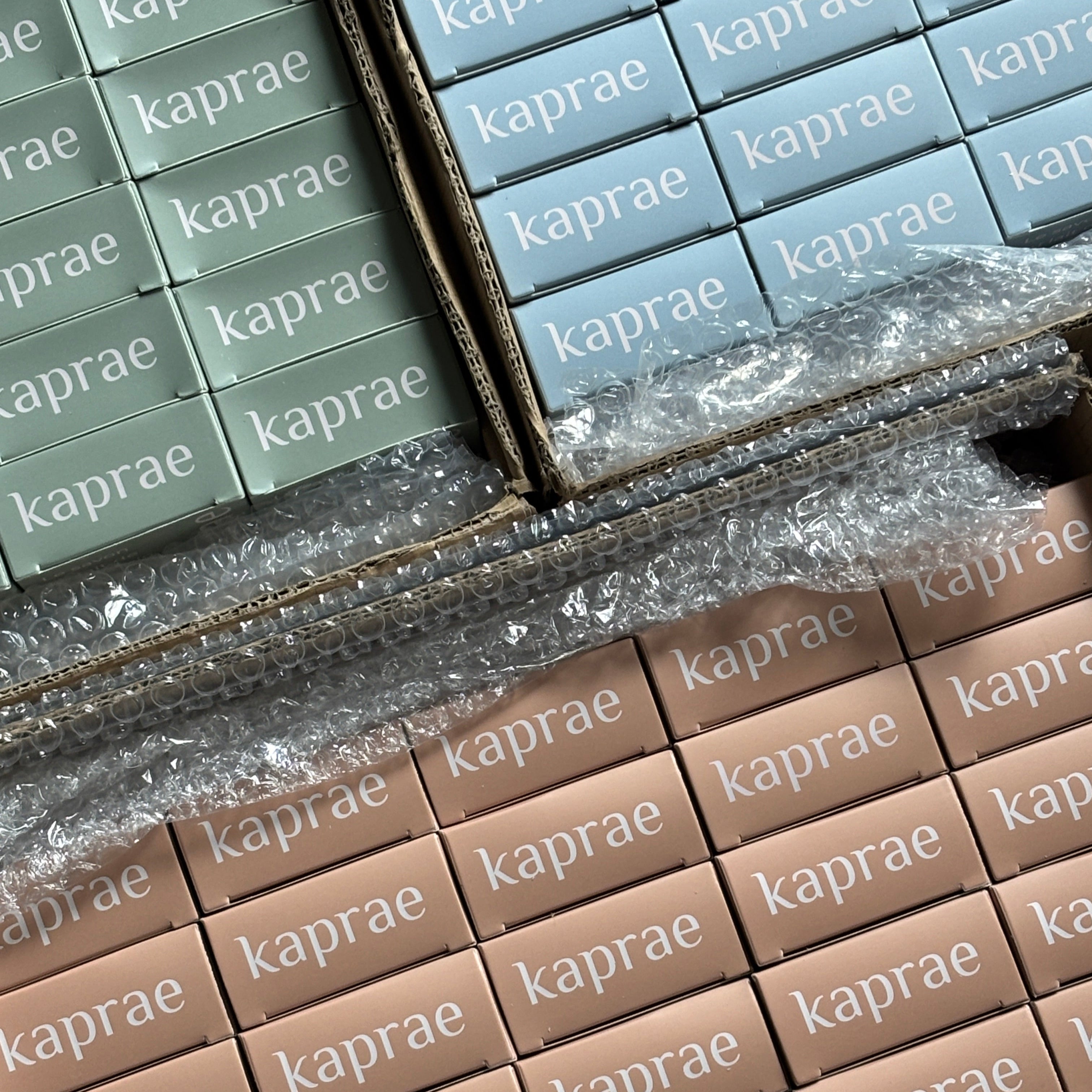 Boîtes de savons Kaprae au lait de chèvre dans leurs packagings colorés vert, bleu et brun. Image